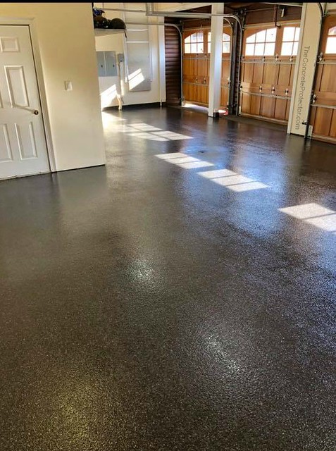 Dark decorative coated garage floor beneath wooden overhead garage doors